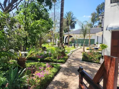 a bench in a garden with flowers and plants at C'est La Vie Boutique Hotel in Witbank