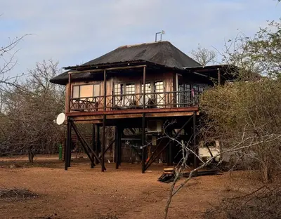 a tree house with a porch and a balcony at Vuurvliegie in Marloth Park
