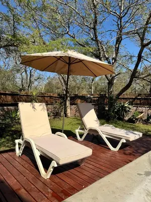 two chairs and an umbrella on a deck at Vuurvliegie in Marloth Park
