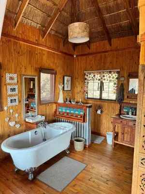 a large bathroom with a tub and wooden walls at Vuurvliegie in Marloth Park