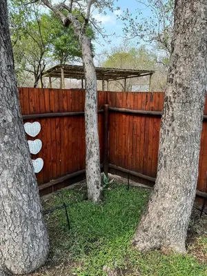 two trees in front of a wooden fence at Sonbesie in Marloth Park