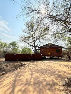 a wooden building with a fence and a tree at Sonbesie in Marloth Park
