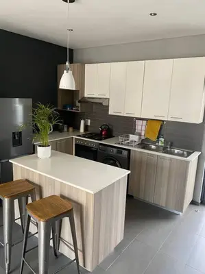 a kitchen with white cabinets and a island with stools at The Blues in Pretoria