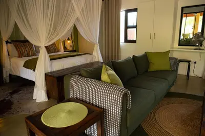 a living room with a couch and a bed at Bee-Eater Cottage in Hoedspruit