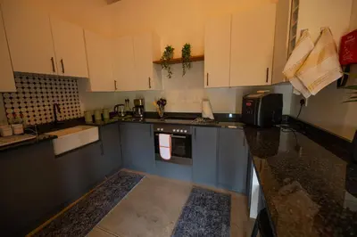 a kitchen with white cabinets and a counter top at Bee-Eater Cottage in Hoedspruit