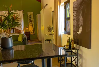 a kitchen with a table and a living room at Bee-Eater Cottage in Hoedspruit