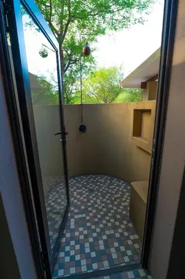 a bathroom with a shower with a tiled floor at Bee-Eater Cottage in Hoedspruit