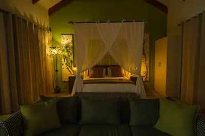 a bedroom with a bed with a couch in it at Bee-Eater Cottage in Hoedspruit