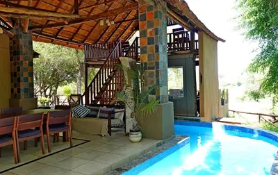 a house with a swimming pool next to a house at Kruger River Holiday Home in Marloth Park