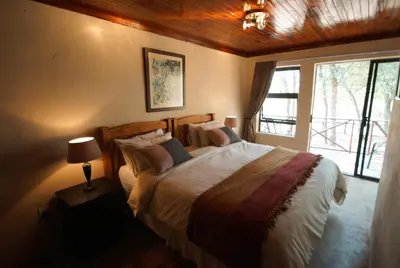 a bedroom with a large bed and a window at Kruger River Holiday Home in Marloth Park