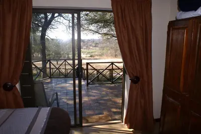 a room with a door open to a patio with a view at Kruger River Holiday Home in Marloth Park