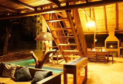 a living room with a couch and a table and a fireplace at Kruger River Holiday Home in Marloth Park
