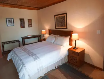 a bedroom with a large bed and two lamps at Kruger River Holiday Home in Marloth Park