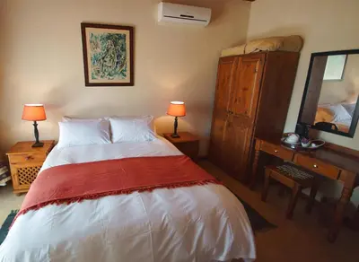 a bedroom with a bed and a dresser and a mirror at Kruger River Holiday Home in Marloth Park