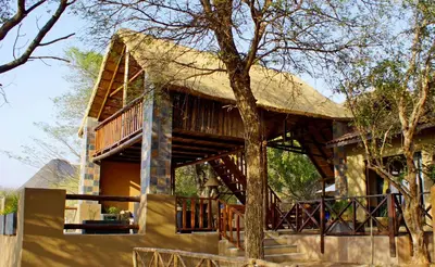 a large house with a thatched roof and stairs at Kruger River Holiday Home in Marloth Park