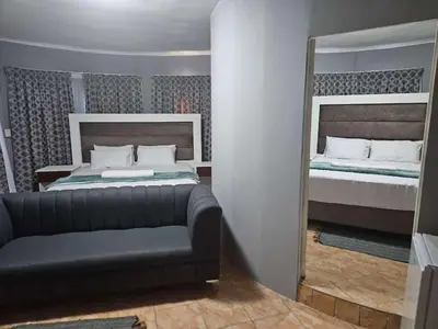 a bedroom with a bed and a mirror and a couch at Marandela Guesthouse in Louis Trichardt