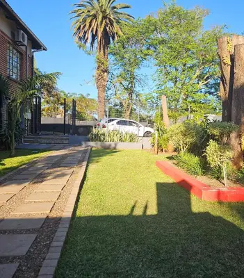 a red bench in a yard with a palm tree at Marandela Guesthouse in Louis Trichardt