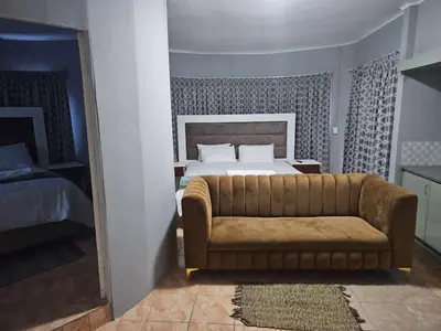 a bedroom with a bed and a couch in it at Marandela Guesthouse in Louis Trichardt