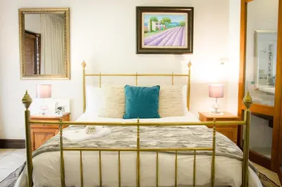 a bedroom with a bed with two lamps and a mirror at De Zoete Rust Guesthouse in Centurion