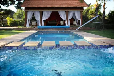 a swimming pool with benches in front of a house at De Zoete Rust Guesthouse in Centurion