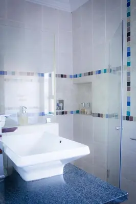 a white bathroom with a sink and a shower at De Zoete Rust Guesthouse in Centurion