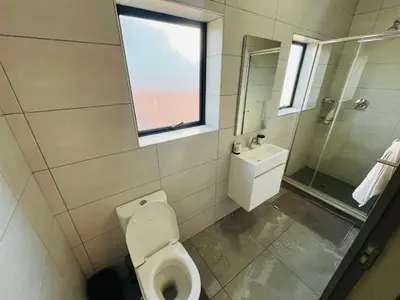 a bathroom with a toilet and a sink and a window at Secure 1 Bedroom Apartment in Midrand, Waterfall City - Lock Up and Go - Free WIFI and Parking - 5 Elizabeth Place in Midrand
