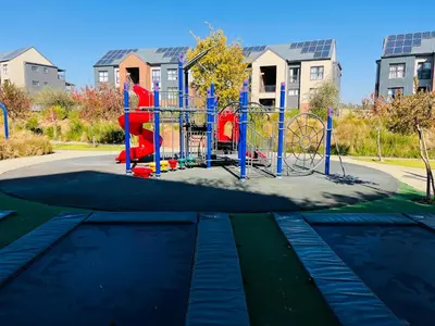 a playground in a park in front of some buildings at Secure 1 Bedroom Apartment in Midrand, Waterfall City - Lock Up and Go - Free WIFI and Parking - 7 Elizabeth Place in Midrand