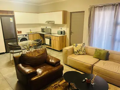 a living room with a couch and a table at Secure 1 Bedroom Apartment in Midrand, Waterfall City - Lock Up and Go - Free WIFI and Parking - 7 Elizabeth Place in Midrand