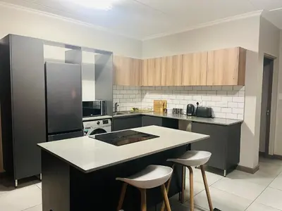 a kitchen with a counter and two bar stools at Spacious 2 Bedroom Apartment in Midrand, Waterfall City - Business and Family friendly - 12 Elizabeth Place in Midrand