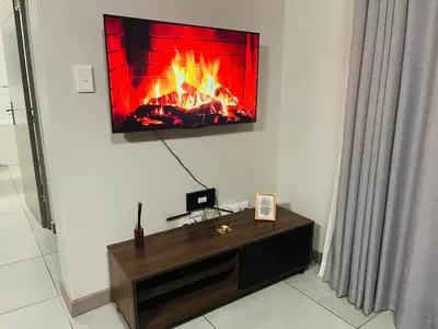 a living room with a fireplace on the wall at Spacious 2 Bedroom Apartment in Midrand, Waterfall City - Business and Family friendly - 12 Elizabeth Place in Midrand