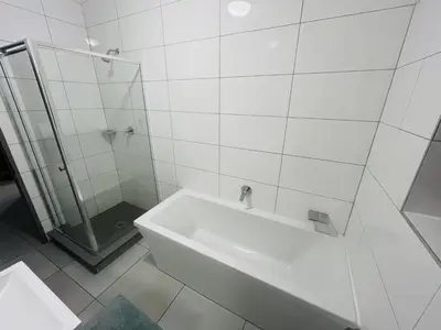 a white tiled bathroom with a shower and a tub at Spacious 2 Bedroom Apartment in Midrand, Waterfall City - Business and Family friendly - 12 Elizabeth Place in Midrand