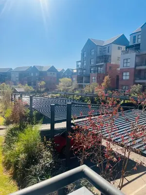 a garden with red plants and buildings in the background at Spacious 2 Bedroom Apartment in Midrand, Waterfall City - Business and Family friendly - 10 Elizabeth Place in Midrand