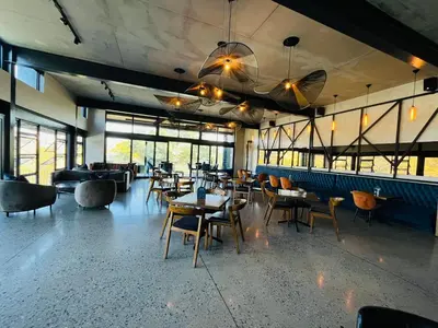 a restaurant with tables and chairs and windows at Spacious 2 Bedroom Apartment in Midrand, Waterfall City - Business and Family friendly - 10 Elizabeth Place in Midrand
