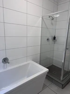 a white bathroom with a shower and a tub at Large 3 Bedroom Apartment in Midrand, Waterfall City - More space than a hotel room - Ideal for families, groups and work trips - 15 Elizabeth Place in Midrand