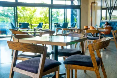 a restaurant with wooden tables and chairs and windows at Large 3 Bedroom Apartment in Midrand, Waterfall City - More space than a hotel room - Ideal for families, groups and work trips - 16 Elizabeth Place in Midrand