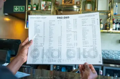 a person holding up a menu in a restaurant at Large 3 Bedroom Apartment in Midrand, Waterfall City - More space than a hotel room - Ideal for families, groups and work trips - 16 Elizabeth Place in Midrand