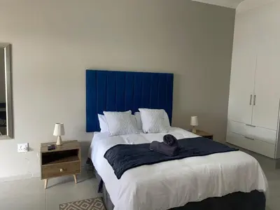 a bedroom with a large bed with a blue headboard at Oaktree in Ermelo