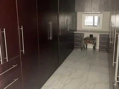 a kitchen with dark wooden cabinets and a table at Oaktree in Ermelo