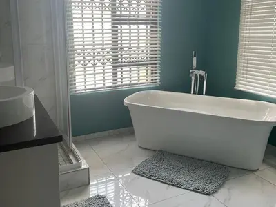 a white bath tub in a bathroom with a window at Oaktree in Ermelo