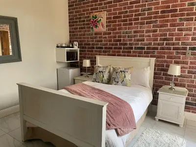 a bedroom with a bed with a brick wall at Oaktree in Ermelo