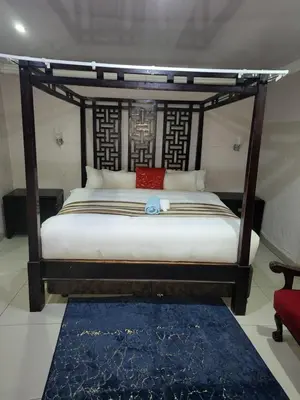 a bedroom with a canopy bed with a blue rug at The wood Guest house in Pretoria