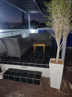 a patio with couches and a table and a tree at The wood Guest house in Pretoria