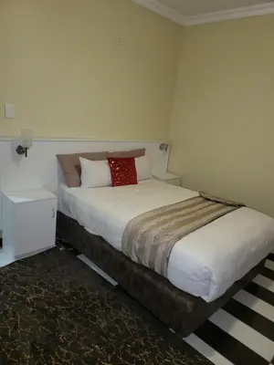 a bedroom with a bed with a red pillow on it at The wood Guest house in Pretoria