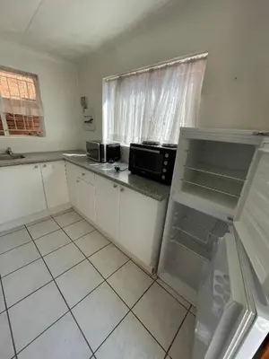 a kitchen with white cabinets and a black microwave at Smartshelter Park in Pretoria