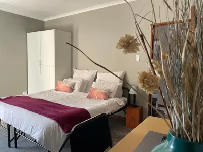 a bedroom with a bed with pillows and a table at Smartshelter Park in Pretoria