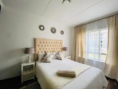 a bedroom with a large bed and a window at Siena Sun Apartment 8 in Midrand