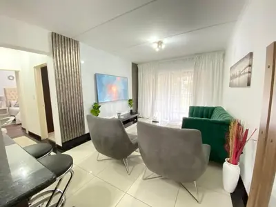 a living room with chairs and a green couch at Siena Sun Apartment 8 in Midrand