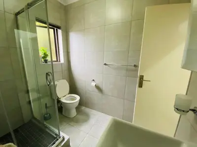 a bathroom with a shower and a toilet and a tub at Siena Sun Apartment 8 in Midrand