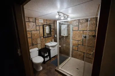 a bathroom with a toilet and a glass shower at 5 Sleeper Bushcamp Chalet Hartbeespoort in Hartbeespoort