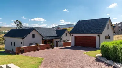 a house with a driveway and a garage at Highland Gate Eagles Breeze in Dullstroom